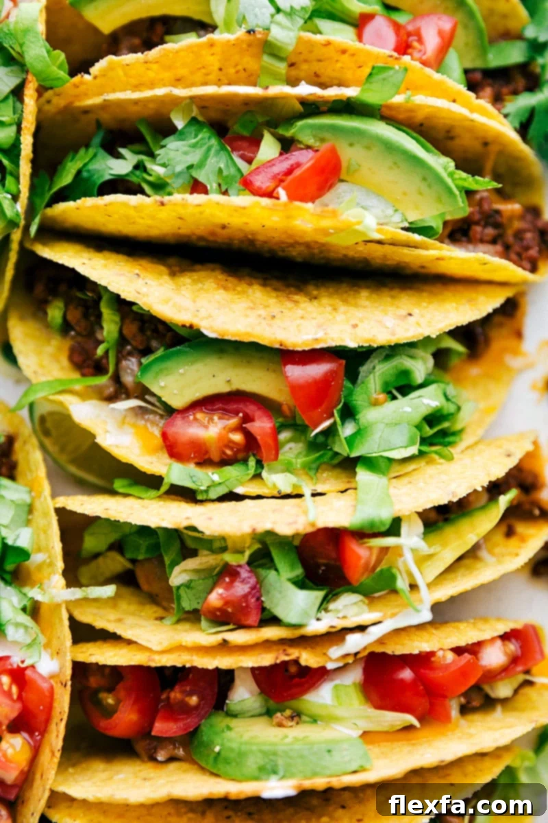 A vibrant casserole dish filled with fully assembled crispy ground beef tacos, bursting with toppings and ready to be served.