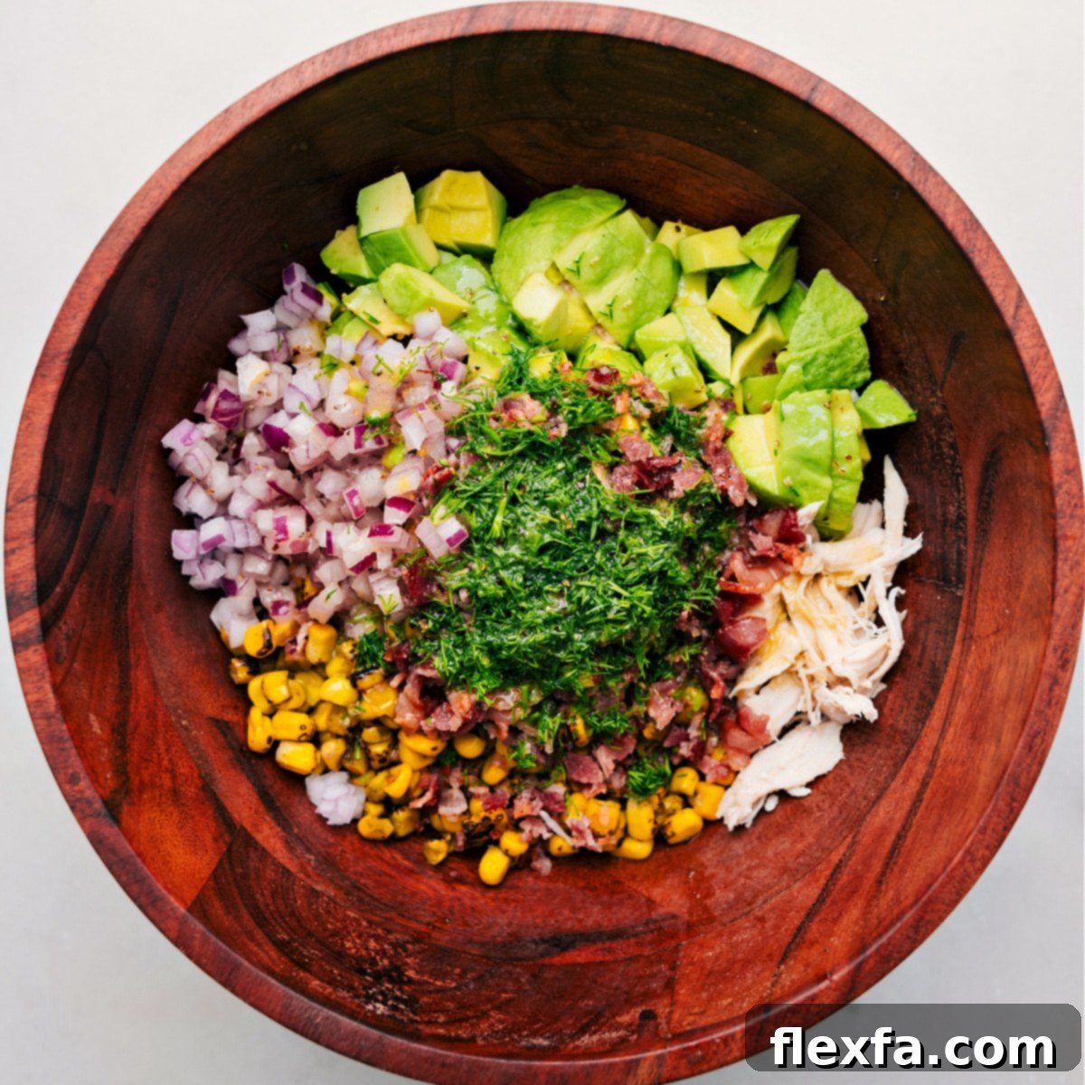 All the ingredients for Chicken Avocado Salad added to a bowl, ready for dressing and tossing.
