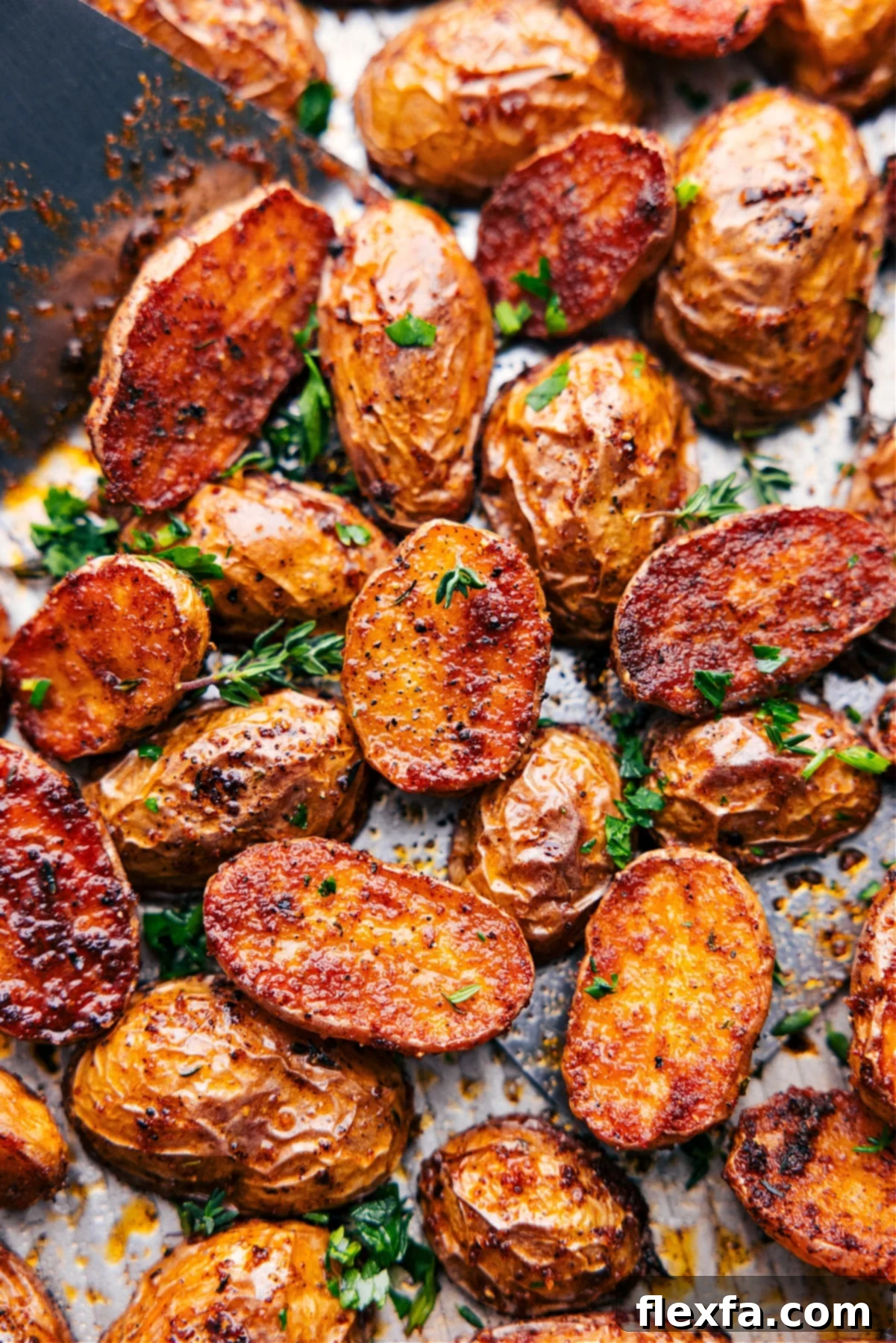 Tray full of crispy golden roasted potatoes, garnished with fresh herbs.