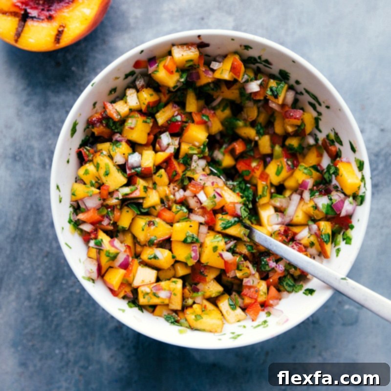A vibrant and fresh bowl of peach salsa, showcasing a colorful mix of diced peaches, red bell pepper, red onion, cilantro, and jalapeño, all perfectly blended and ready to serve.