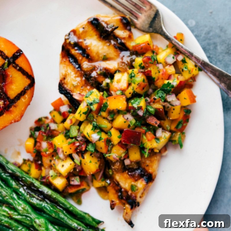 A delicious and vibrant dish of grilled chicken generously topped with fresh peach salsa, perfectly paired with bright green beans on the side, ready to be enjoyed.