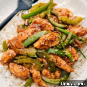 Black Pepper Chicken served with rice, garnished with sesame seeds.