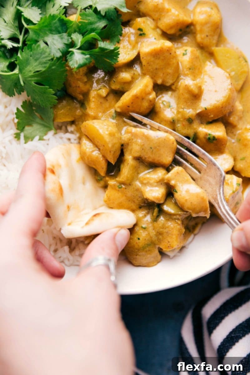 Rich Yellow Chicken Curry served over a bed of fragrant basmati rice, with a piece of naan bread ready for dipping, highlighting the creamy sauce and tender chicken and potatoes.