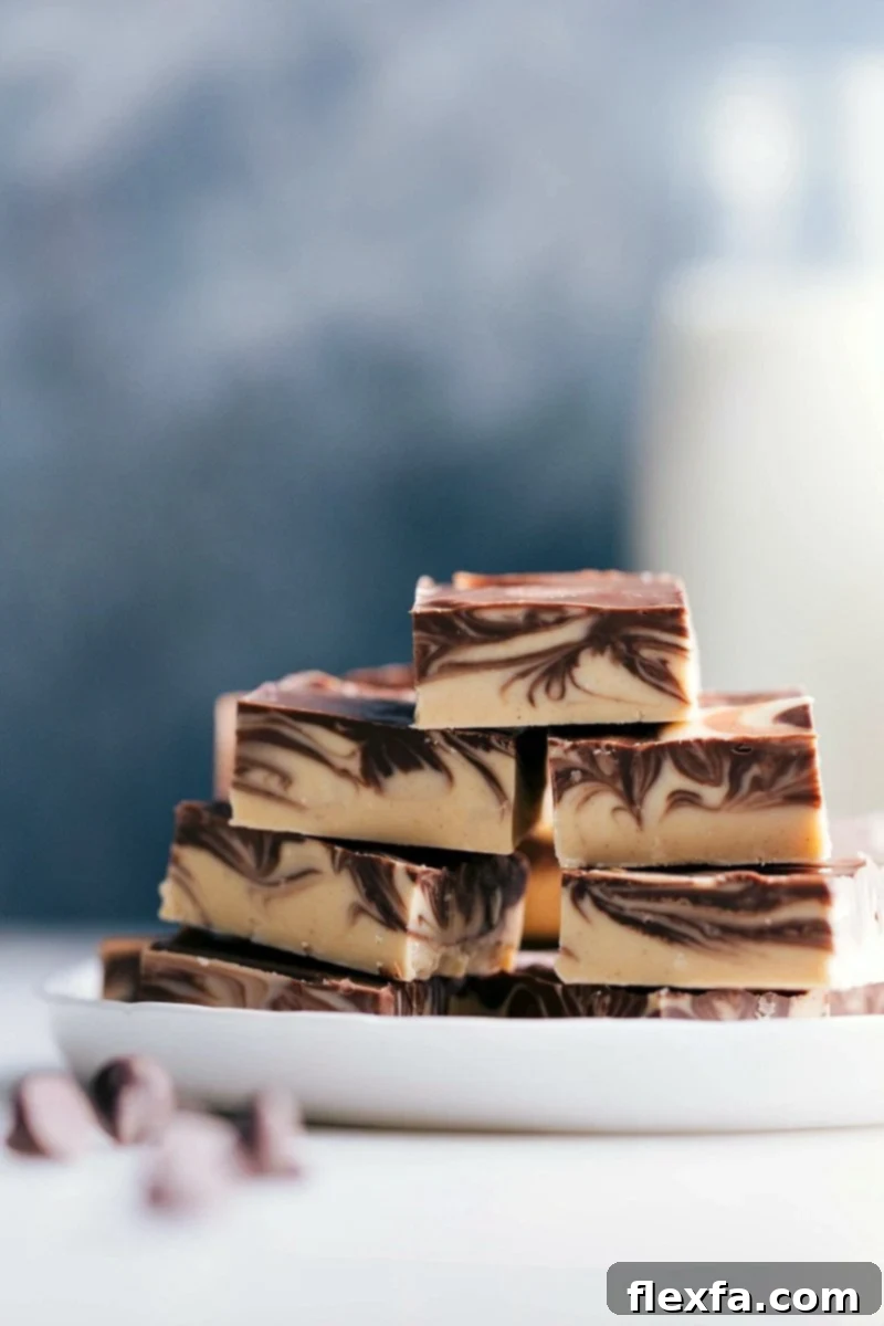Stacked slices of tiger butter fudge with distinctive chocolate and peanut butter swirls, showcasing its appealing marbled pattern and inviting texture.