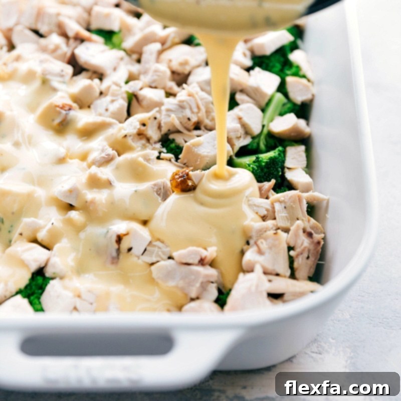 Pouring creamy, cheesy sauce over the dish in preparation for cooking.