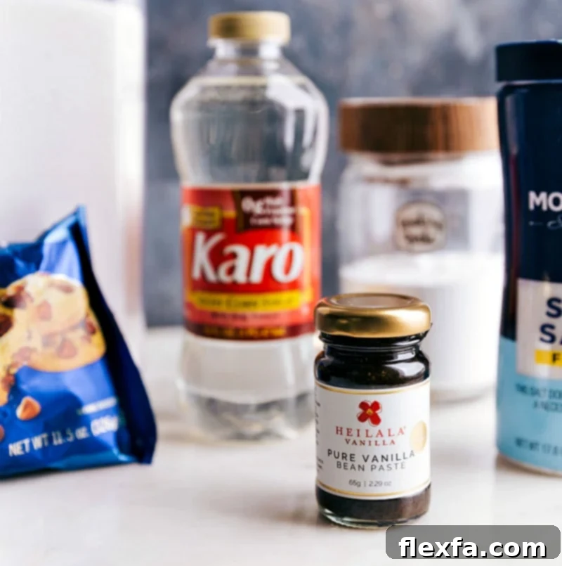 A selection of essential ingredients for making Honeycomb Candy laid out on a clean surface: a bowl of granulated sugar, a measuring cup of light corn syrup, baking soda, vanilla extract, and a pinch of salt.