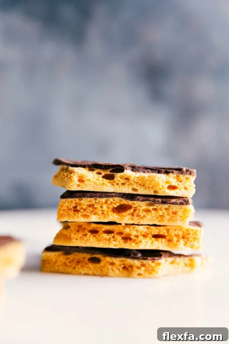 Beautifully stacked pieces of golden Honeycomb Candy, some plain and some elegantly drizzled with chocolate, showcasing their inviting texture.