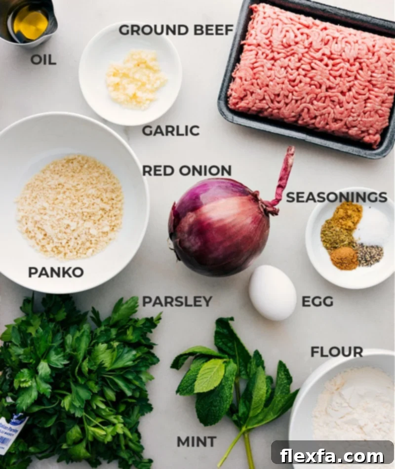 A flat lay image displaying all fresh ingredients laid out for making Greek Meatballs, including ground beef, panko breadcrumbs, fresh parsley, mint, red onion, garlic cloves, olive oil, and various Mediterranean spices.