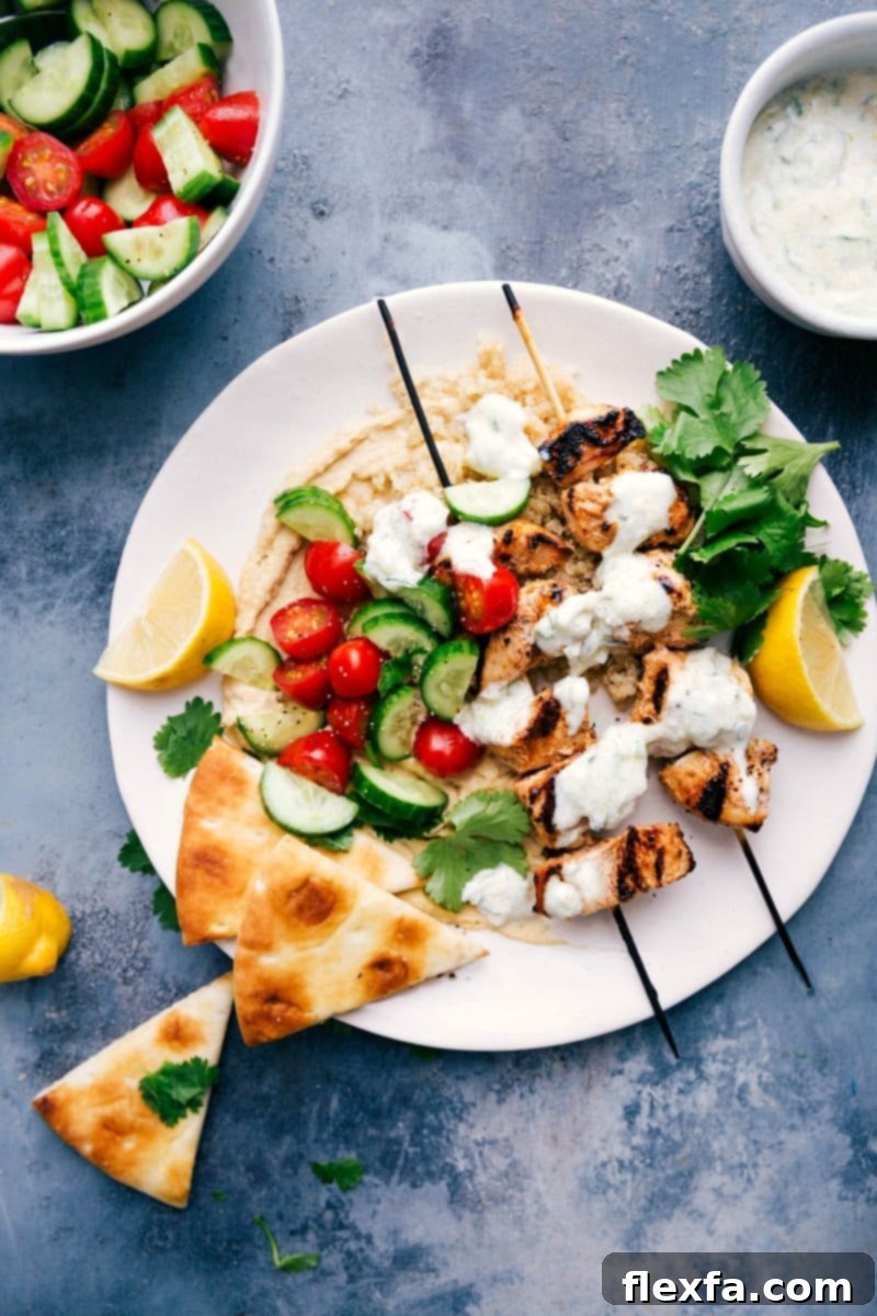 Shish tawook skewers served atop creamy hummus, ready to eat.