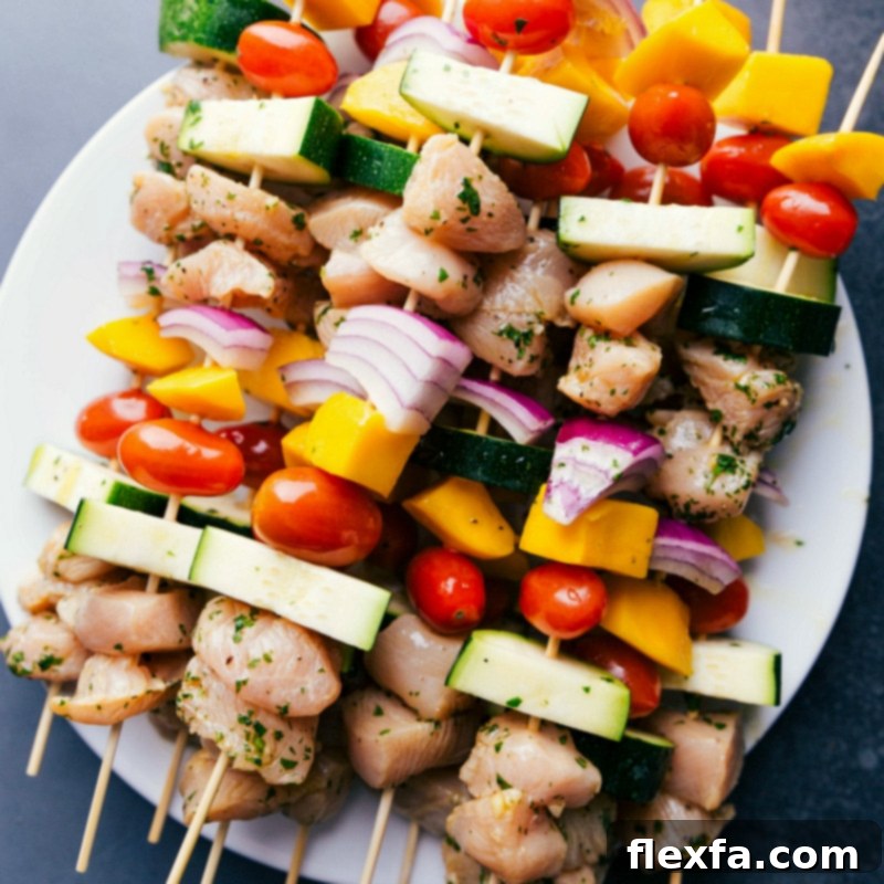 Preparing Chicken Kabobs for Grilling Uncooked chicken kabobs recipe, prepared with chicken, mango, onions, zucchini, and tomatoes threaded onto skewers, ready for grilling.