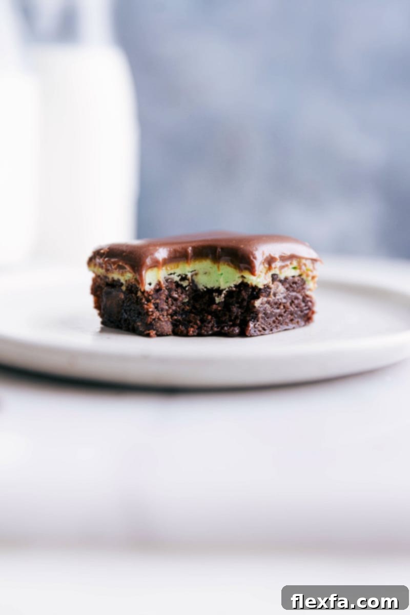 A delicious mint chocolate brownie on a plate with a bite taken out of it, showing its layers of chocolate, mint, and ganache.