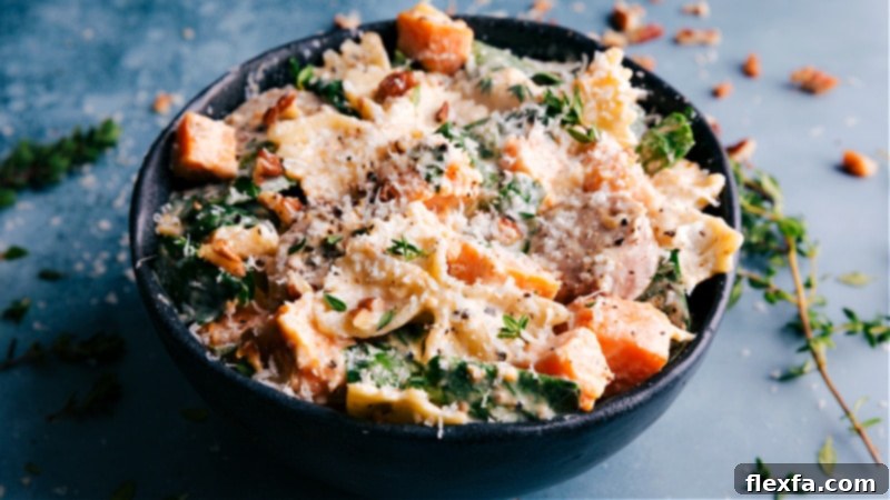 An indulgent Sweet Potato Pasta, where roasted sweet potatoes, onions, and chicken sausage are tossed in an unforgettable creamy goat cheese sauce and topped with Parmesan. Recipe via ChelseasMessyApron. Image of Sweet Potato Pasta served in a bowl, garnished