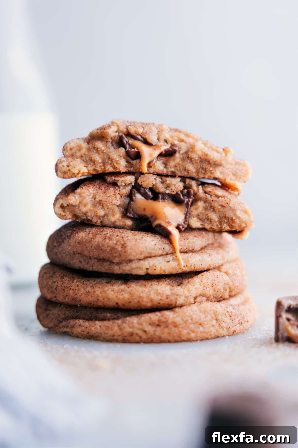 A perfectly arranged stack of soft, chewy caramel snickerdoodles, showcasing their gooey, melting caramel and chocolate centers. The rich cinnamon sugar coating shimmers under the light, inviting a bite.