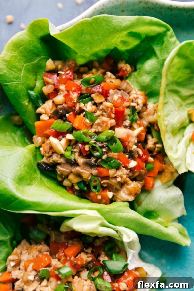 Beautifully plated chicken lettuce wraps, garnished with fresh herbs, lime wedges, and chopped peanuts, ready to be enjoyed as a healthy and flavorful meal.