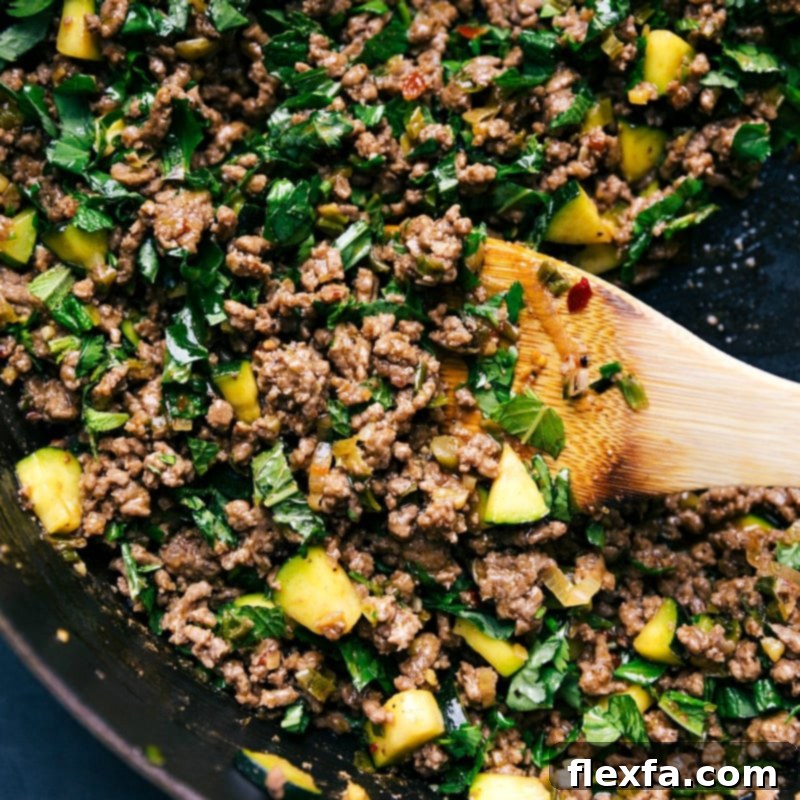 A wooden spoon serving a portion of the finished larb beef dish directly from the pan, highlighting its appealing texture and rich color.