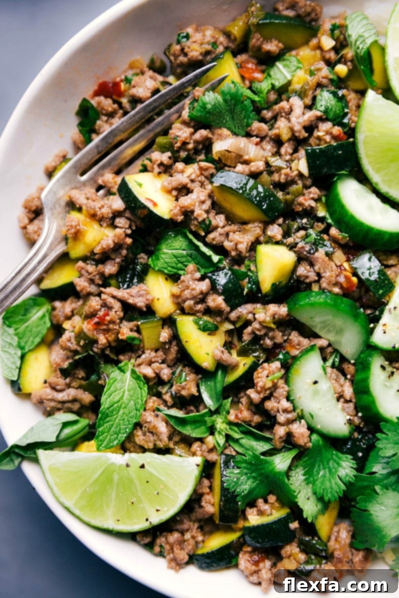 A beautifully plated dish of ready-to-eat Beef Larb, garnished with fresh lime wedges and vibrant herbs, with a fork resting beside it, inviting you to enjoy.
