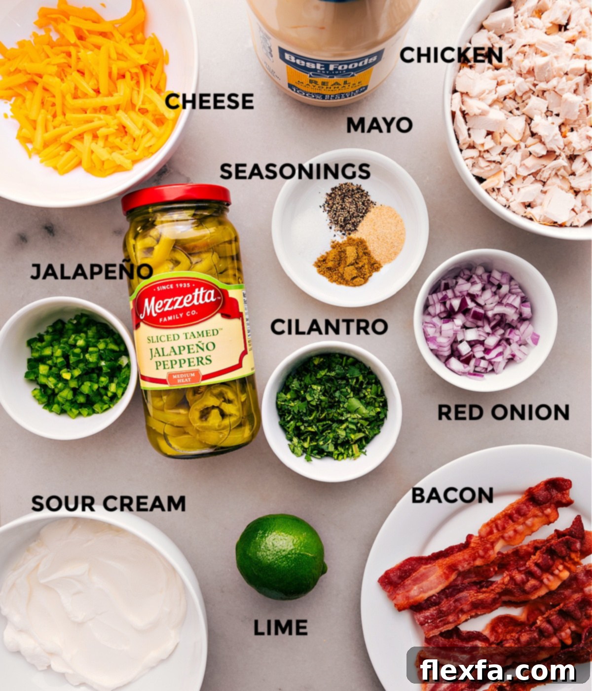 All the essential ingredients for Jalapeño Popper Chicken Salad, neatly prepped and displayed: diced chicken, shredded cheddar, crispy bacon, fresh and jarred jalapeños, red onion, cilantro, and dressing components like mayo and sour cream.