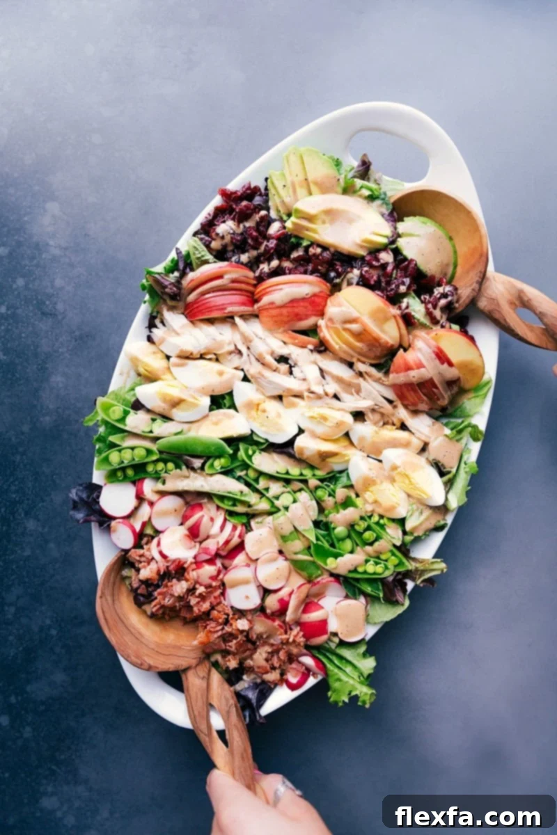 Lavish Cobb Salad Presentation with a Medley of Ingredients and Creamy Balsamic Dressing A generous serving platter heaped with a cobb salad masterpiece, boasting meats, fresh vegetables, fruit, and drizzled with creamy balsamic dressing.