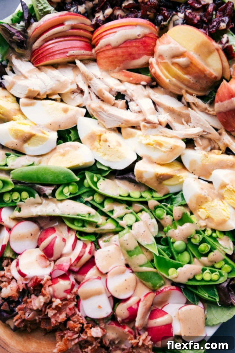 Vibrant Finished Salad with Apples, Chicken, Eggs, Peas, and Radishes Completed salad, artfully arranged to highlight apples, chicken, hard-boiled eggs, sugar snap peas, and radishes, waiting to be served.