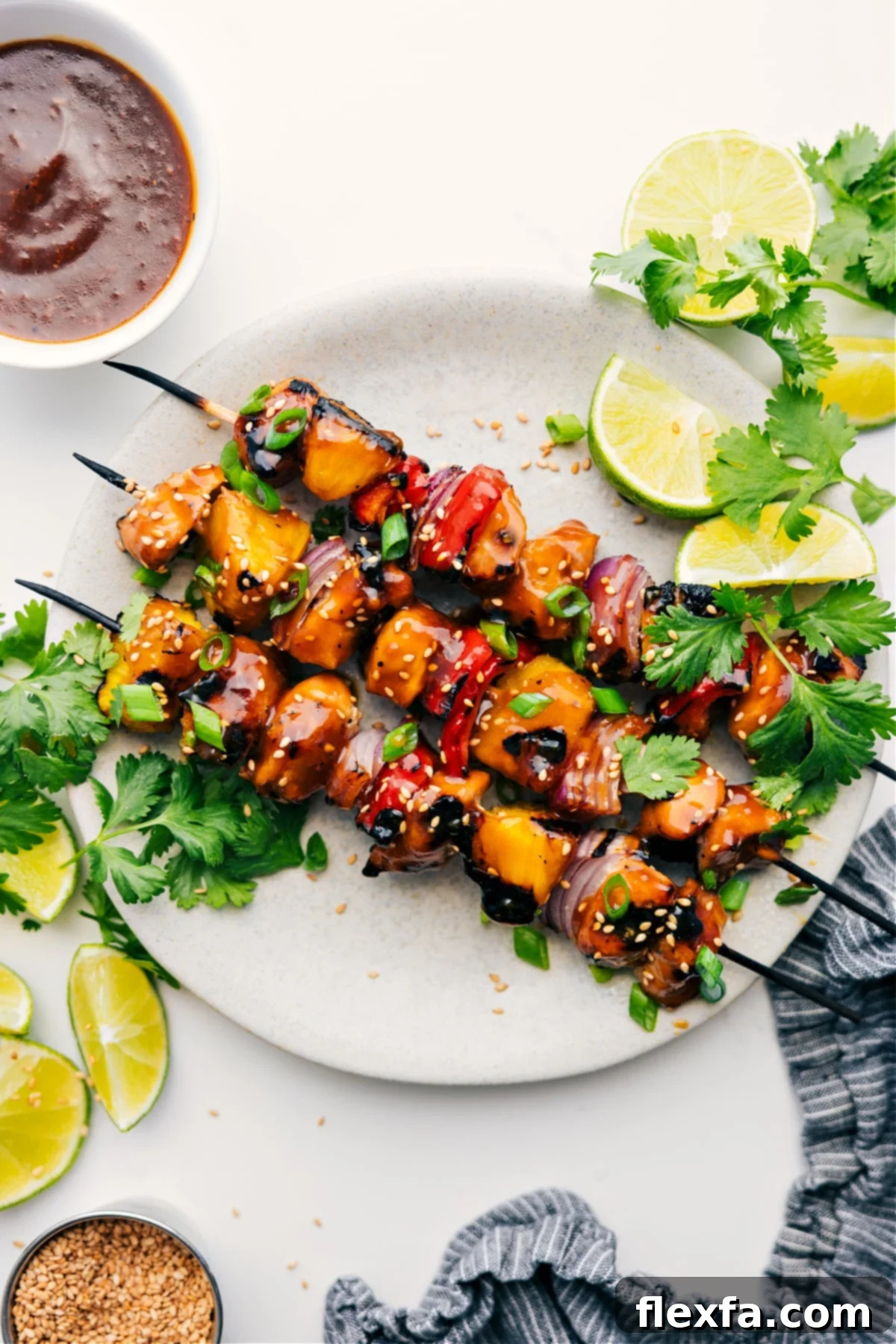 Teriyaki Chicken Skewers served with lime wedges, fresh cilantro, and a side of dipping sauce, showcasing a vibrant and appealing meal.