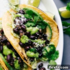 Savory Black Bean Tacos 2 Black bean tacos with cilantro sauce and limes, ready to eat.