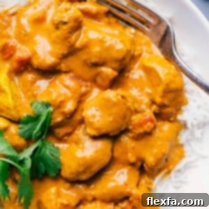 A plate featuring a generous serving of creamy Butter Chicken, elegantly plated over white rice and ready to be enjoyed.