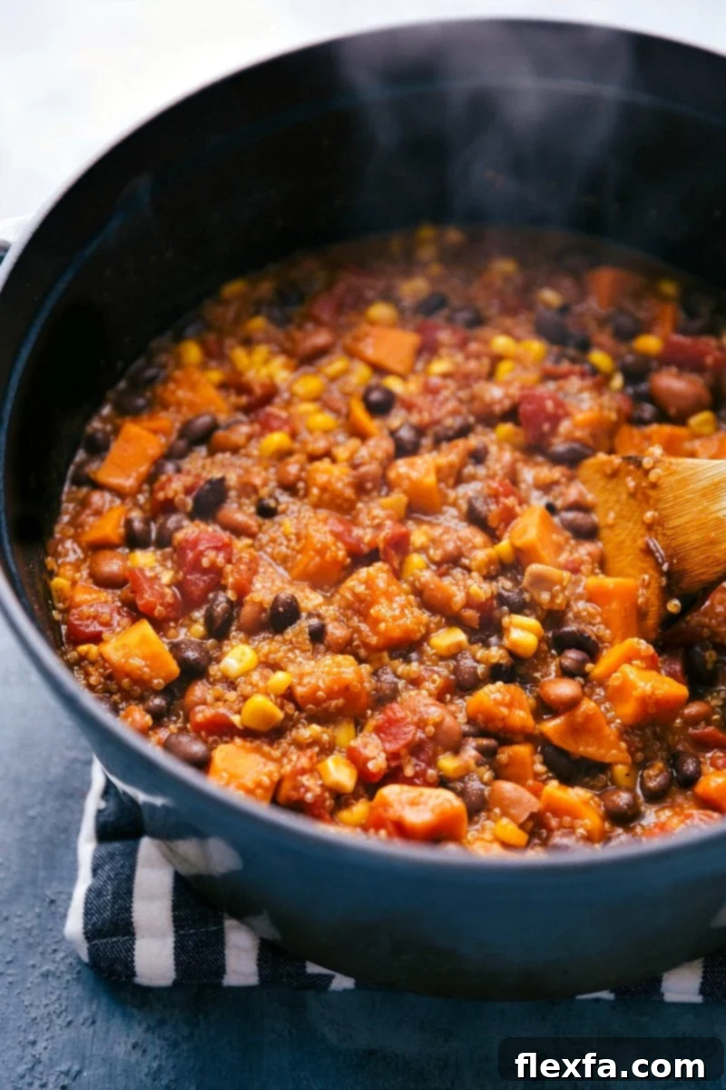 A large pot filled with warm, bubbling Quinoa Chili, topped with fresh cilantro, ready to be served. This hearty and healthy vegetarian meal is perfect for a cozy dinner.