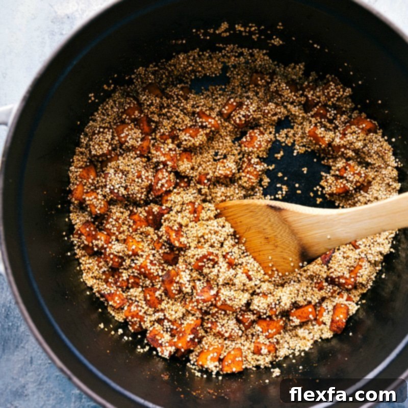 Rinsed quinoa being carefully added to a pot filled with sautéed sweet potatoes and spices, ready to absorb the rich flavors and liquids to create the chili.