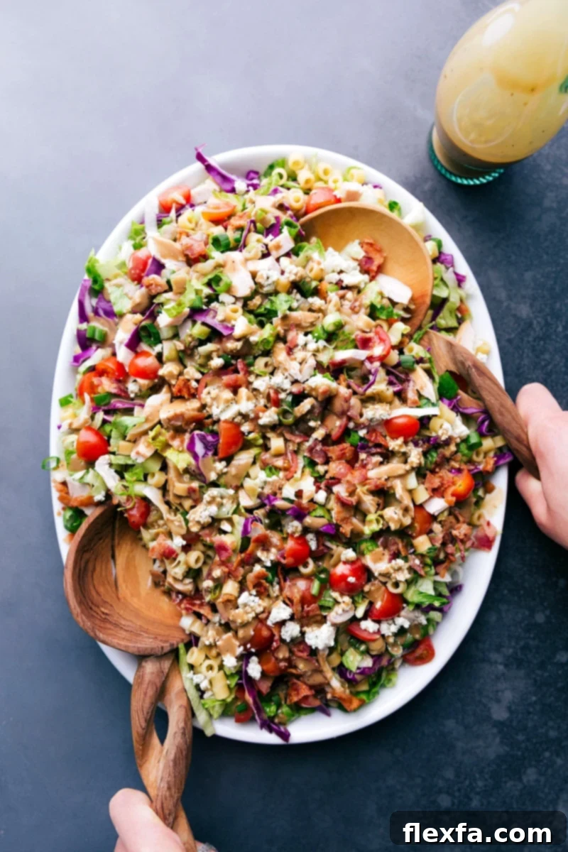 A vibrant bowl of Portillo's Chopped Salad, showcasing its rich colors and ingredients, served with two elegant serving spoons.