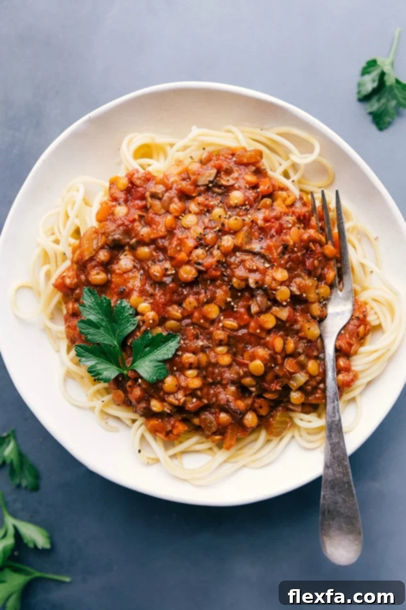 Savory Lentil Bolognese on Spaghetti - A Delicious and Fulfilling Plant-Based Dish Lentil bolognese served generously over a bed of perfectly cooked spaghetti, garnished with fresh basil or parsley, showcasing a visually appealing, savory, and mouth-watering vegan meal.