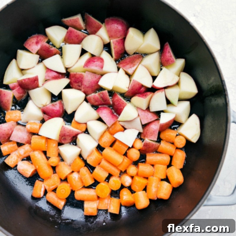 Sautéing red potatoes and carrots in a large skillet for a healthy one-skillet lemon chicken meal.