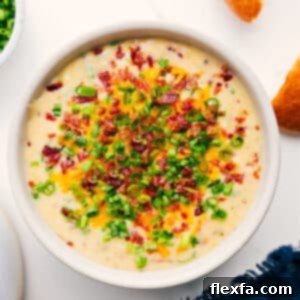 Close-up of a bowl of creamy Loaded Potato Soup, garnished with bacon, cheese, and chives.