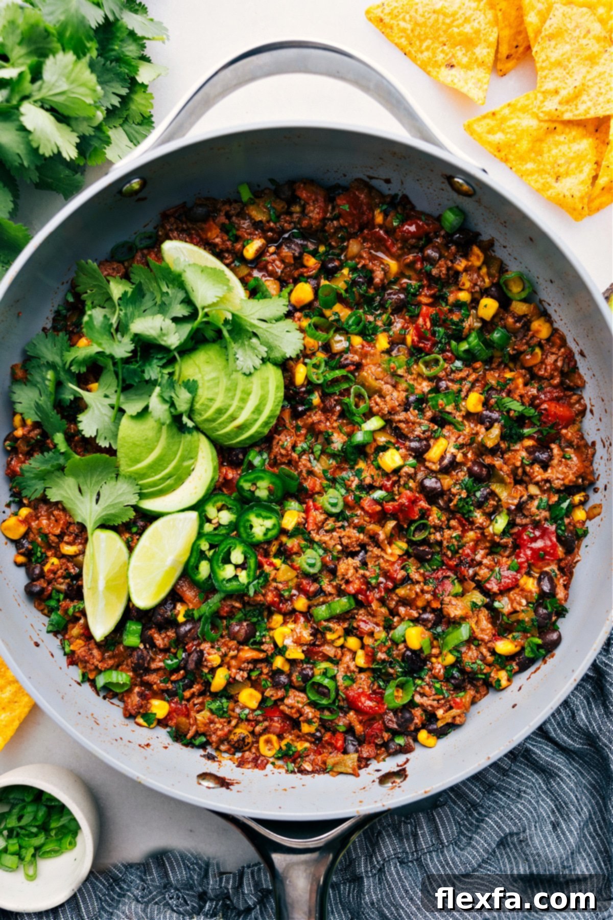 A vibrant Taco Skillet in a rustic pot, beautifully garnished with fresh avocado slices, bright cilantro, a wedge of lime, and spicy jalapeños, ready to be enjoyed.