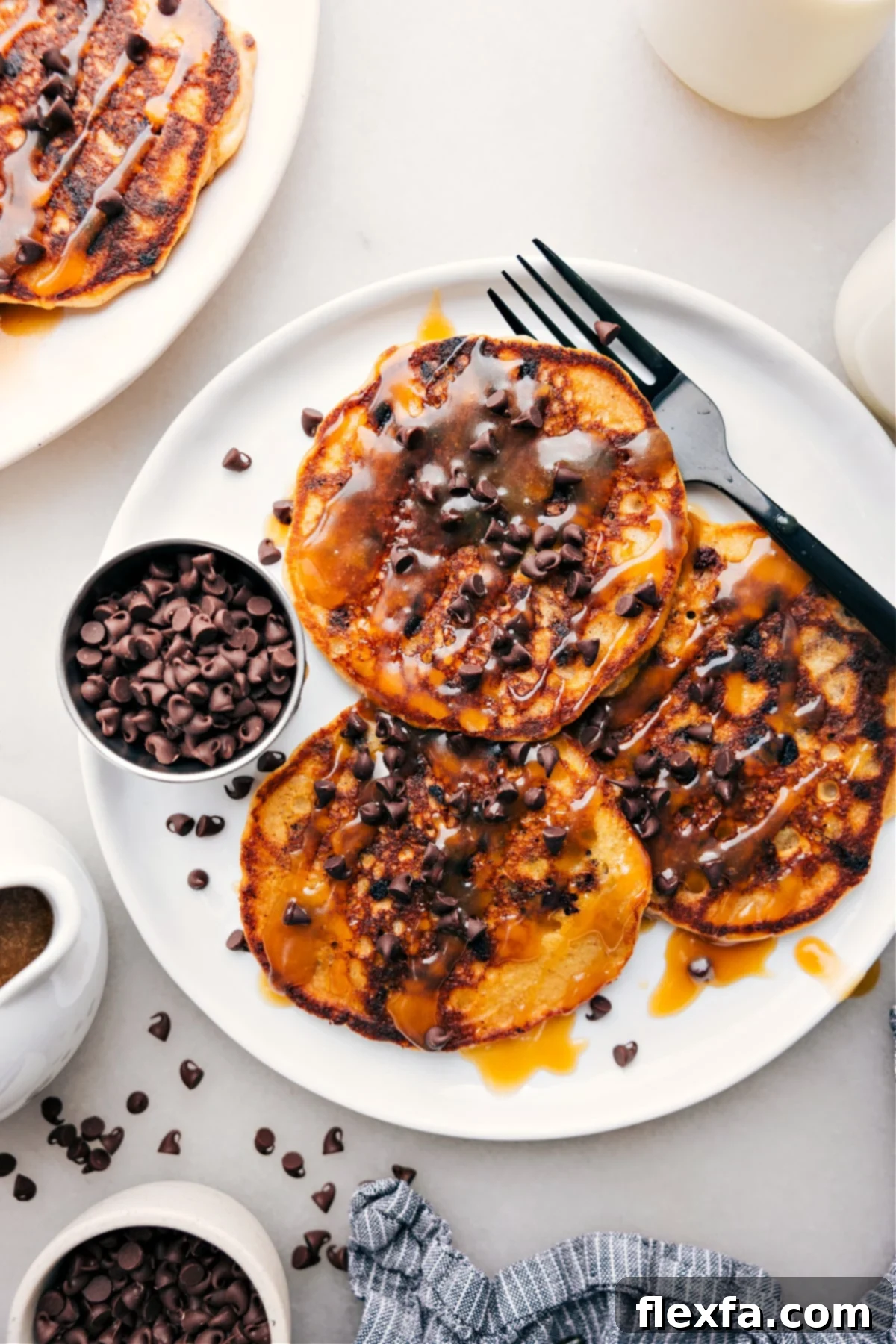 Irresistible Chocolate Chip Pancakes 2 Perfectly stacked chocolate chip pancakes drizzled with maple syrup, ready for a delicious breakfast.