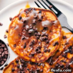 A stack of golden brown chocolate chip pancakes with melty chocolate chips visible.