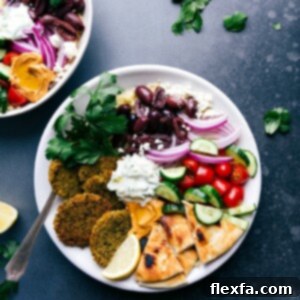 Baked falafel served on a plate with pita bread, tzatziki sauce, olives, onions, tomatoes, and cucumbers.