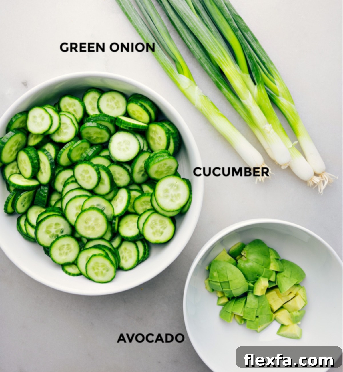 The three core ingredients for this simple Asian Cucumber Salad laid out: sliced cucumbers, avocado, and green onions.