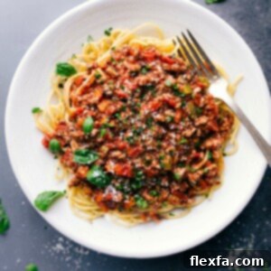 Savory and delicious turkey bolognese on a bed of spaghetti, topped with fresh herbs.