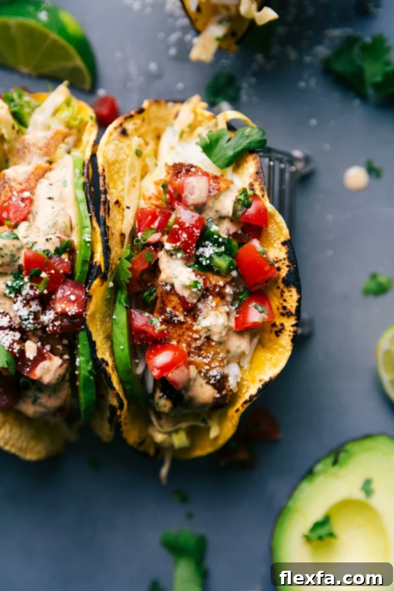 Two gourmet fish tacos bursting with seasoned fish, fresh pico de gallo, and creamy sauce, ready to be enjoyed.