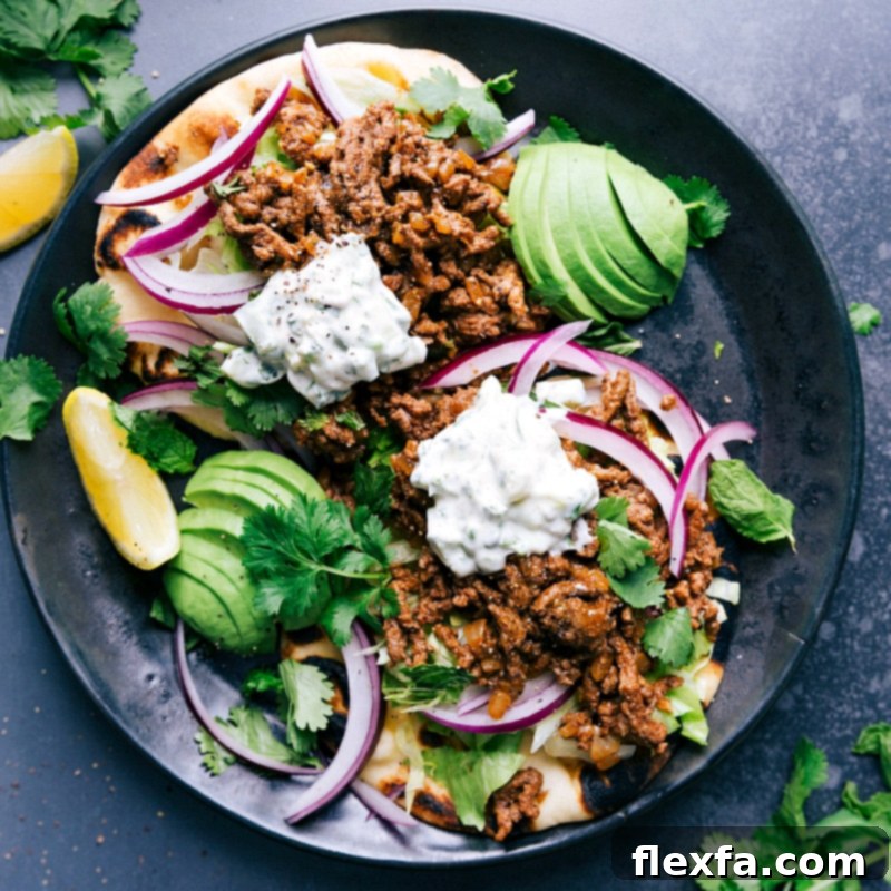 Ground Beef Naan Tacos - A Flavorful Feast The finished meal topped with delicious toppings, sauce, and vegetables, creating a delicious meal.
