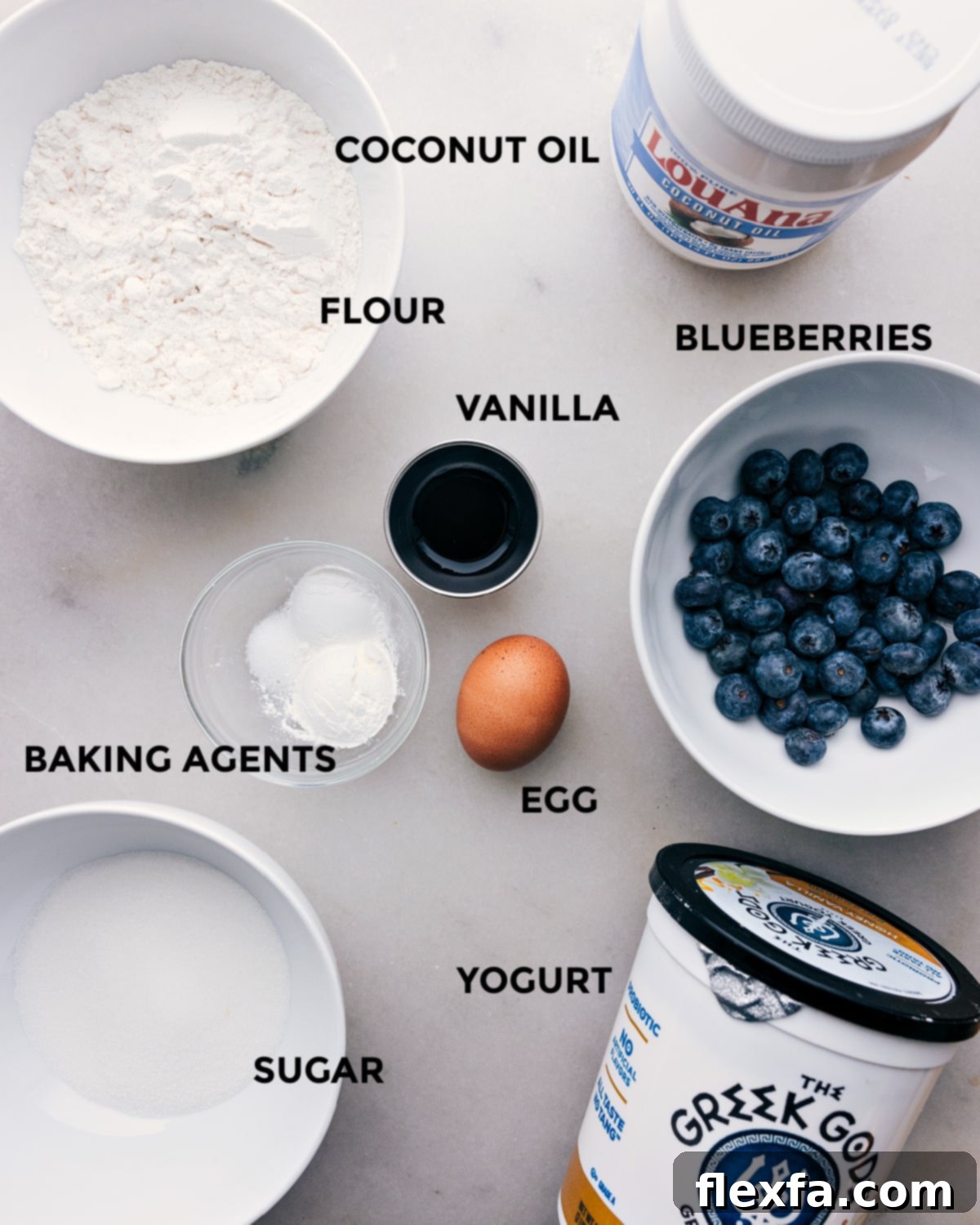 A vibrant flat lay photograph showcasing all the fresh, natural, and wholesome ingredients arranged neatly on a surface, ready for making healthy blueberry muffins.
