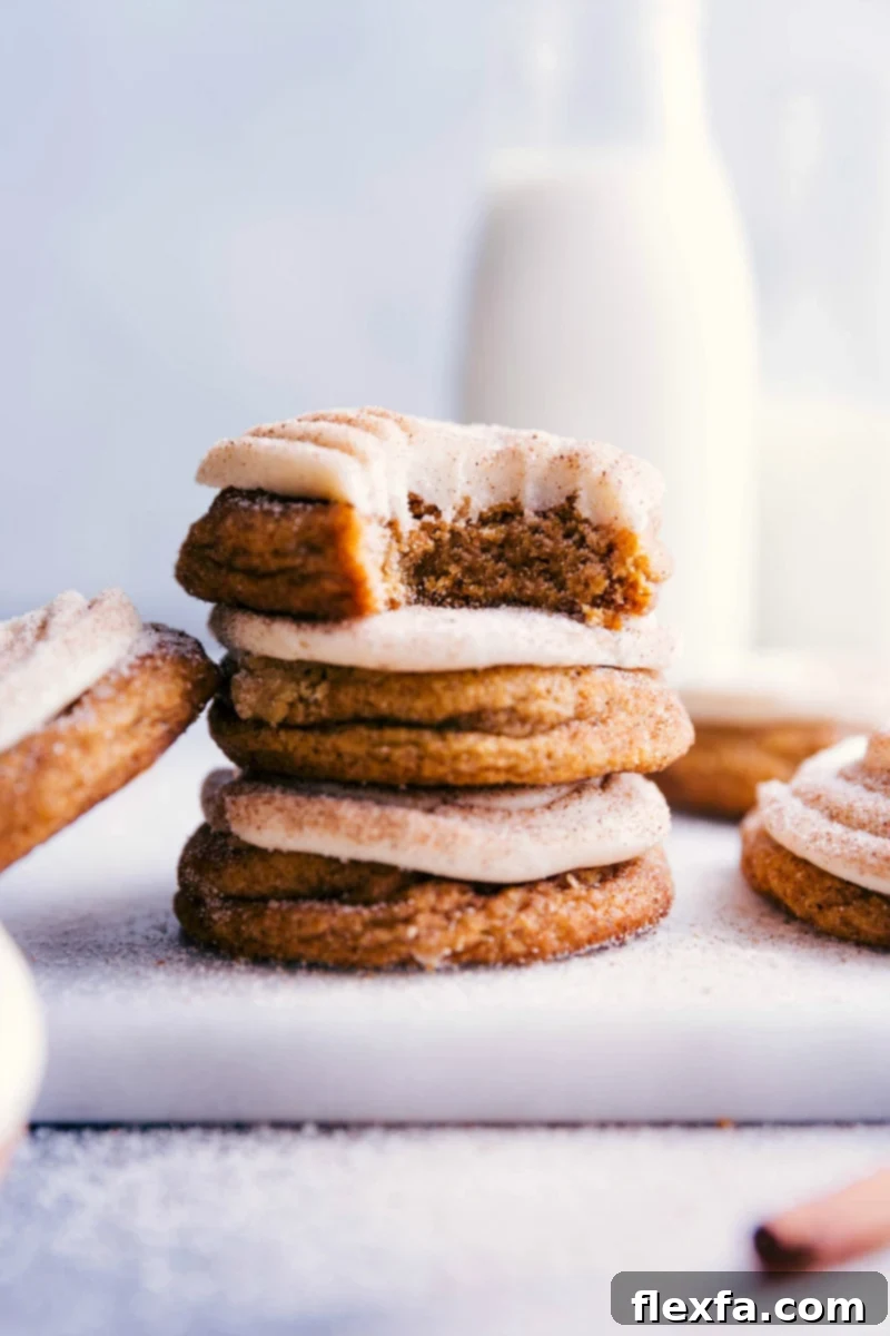 Pumpkin Cinnamon Roll Cookies - Stack with Bite Mark, Fluffy Interior, and Frosting Stacked pumpkin cinnamon roll cookies with a bite taken out of the top one, revealing their fluffy interior and delightful frosting.