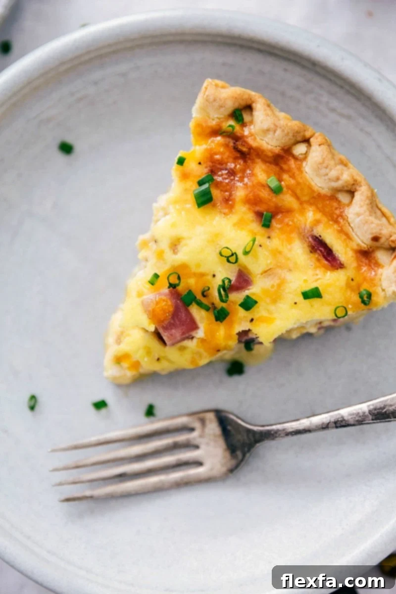 A delectable slice of ham and cheese quiche, perfectly baked with a golden crust and creamy filling, presented beautifully on a plate.