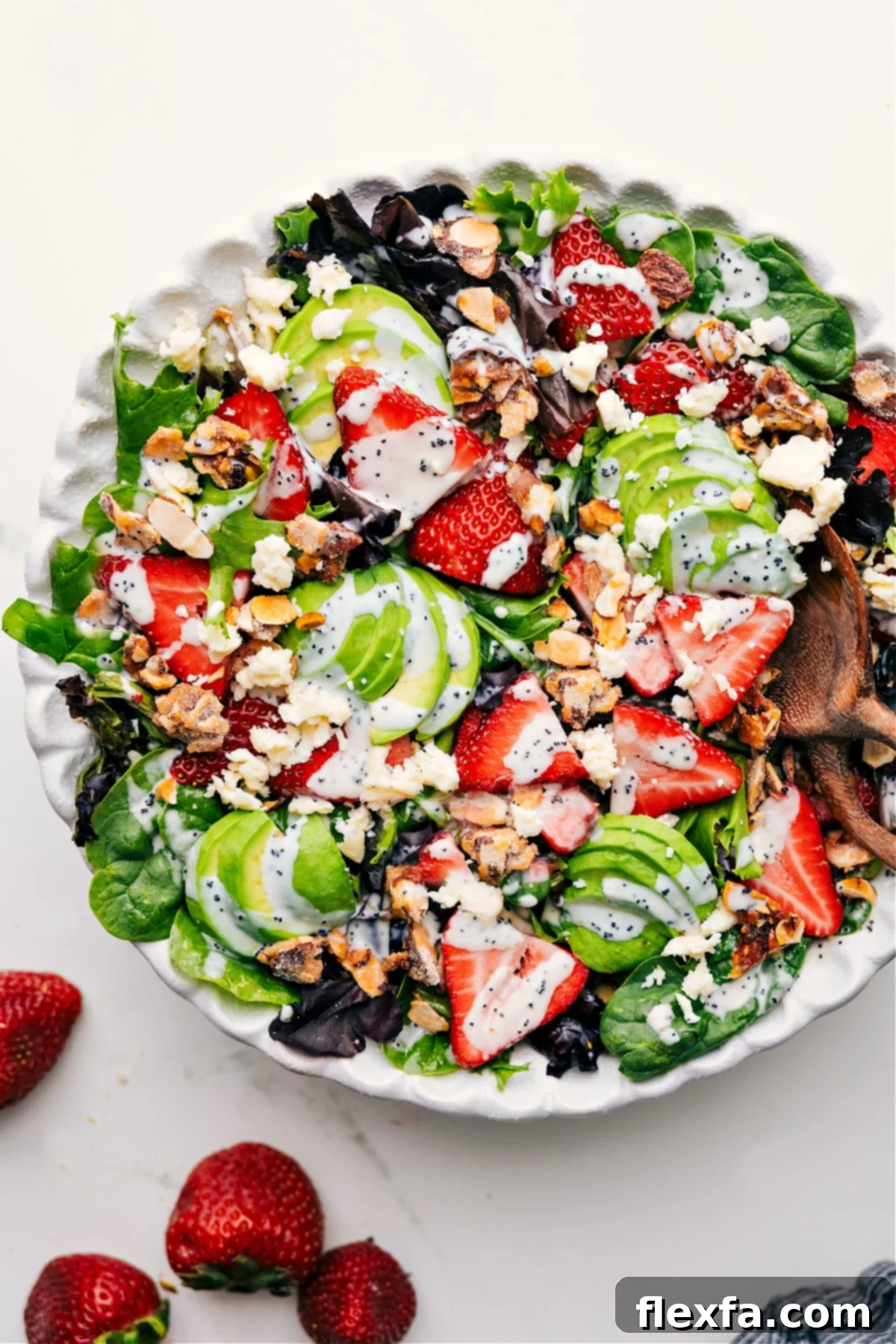 Vibrant Strawberry Poppyseed Salad tossed in a bowl, drizzled with creamy dressing, ready to be served.