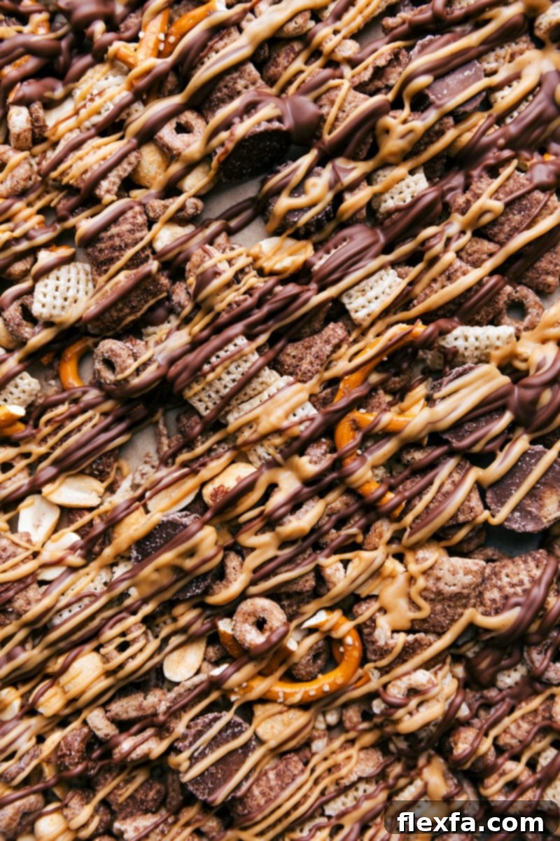 Chex Mix Perfection - Chocolate Peanut Butter Snack Mix Ready to Delight The completed batch of Chocolate Peanut Butter Snack Mix is showcased in a vibrant, inviting close-up. Each piece is perfectly coated with drizzles of chocolate and peanut butter, highlighting the varied textures of cereals, nuts, pretzels, and miniature peanut butter cups. The snack mix looks utterly delicious and ready for immediate enjoyment, embodying the ultimate sweet and salty crunch.