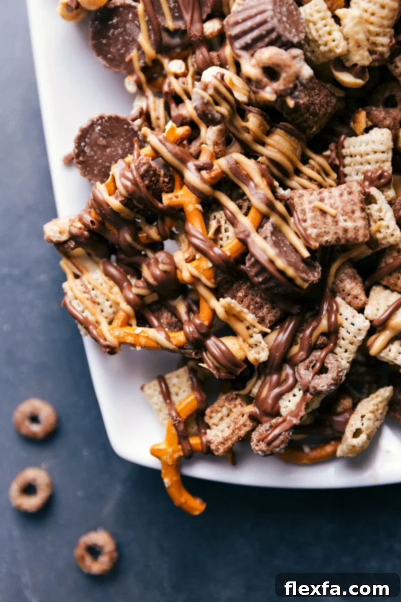 Dessert Ready to Impress - Served on a Platter for Enjoyment A beautifully arranged serving platter holds a generous portion of the finished Chocolate Peanut Butter Snack Mix. The various components like cereals, pretzels, peanuts, and Reese's minis are visible, all coated in enticing chocolate and peanut butter drizzles. The snack is ready to be presented and enjoyed, highlighting its delicious appeal.