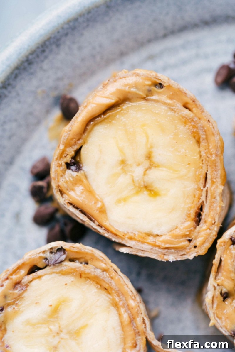 Cross-section view of colorful Banana Sushi Bites, revealing layers of tortilla, peanut butter, granola, and a banana center.