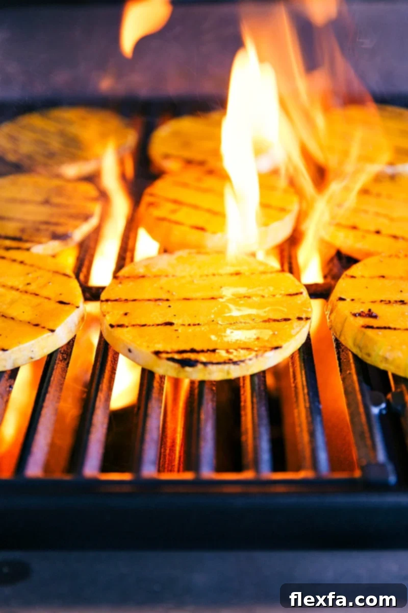 Close-up image of butternut squash slices grilling over open flames, showcasing the charring process.