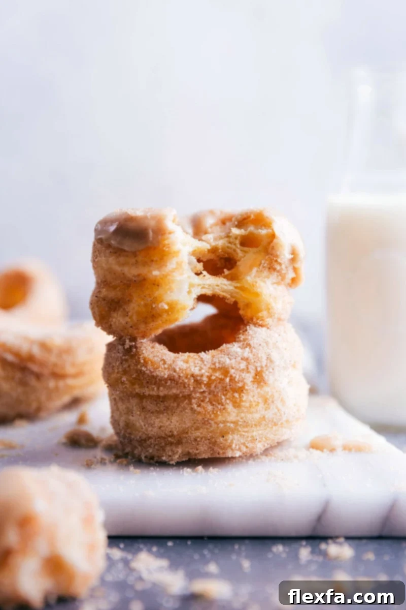 Close-up of two cronuts, one revealing its fluffy, layered interior after a bite, highlighting the delicious texture.