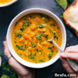 A vibrant and appetizing bowl of warm sweet potato coconut curry soup, garnished with fresh cilantro, ready to be enjoyed.